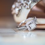 Elegant engagement ring on a shimmering surface with bridal details in the background