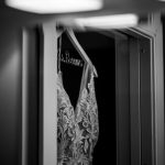 Lace bridal gown on a custom hanger reflected in a mirror.