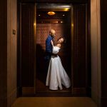 Bride and groom share a joyful moment inside a vintage-style elevator on their wedding day