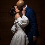 Bride and groom share an intimate kiss in low, dramatic lighting on their wedding day
